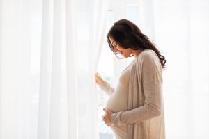 graviditet, moderskap, människor och förväntan koncept - närbild av lycklig gravid kvinna med stor mage vid fönstret