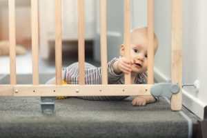 Child,Playing,Behind,Safety,Gates,In,Front,Of,Stairs,At